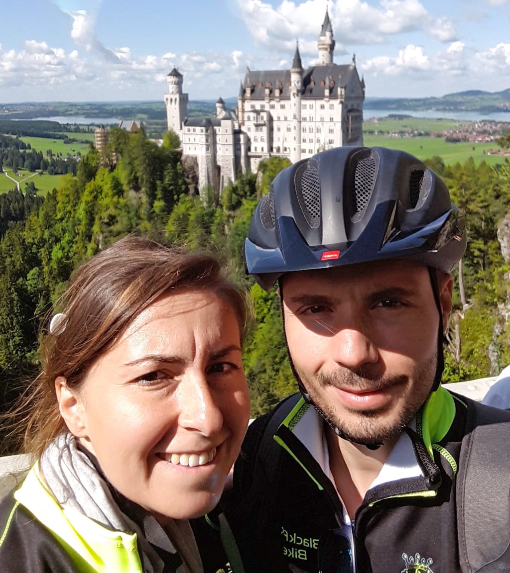 Coppia in bici lungo la Romantische Strasse, Germania, con casco e abbigliamento da cicloturismo.